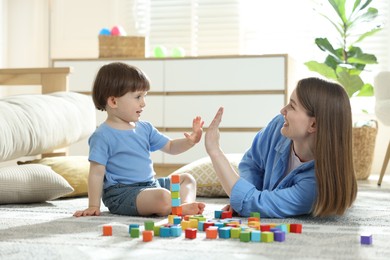 Photo of Mother and son giving high five while playing with colorful cubes at home