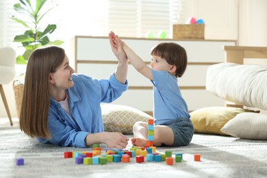 Photo of Mother and son giving high five while playing with colorful cubes at home