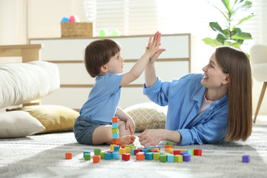 Photo of Mother and son giving high five while playing with colorful cubes at home