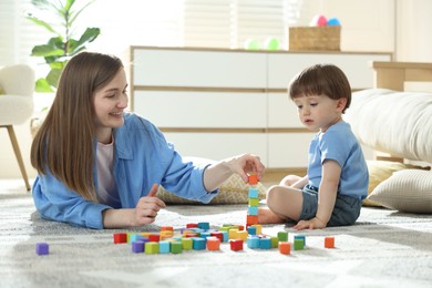 Photo of Mother and son playing with colorful cubes at home