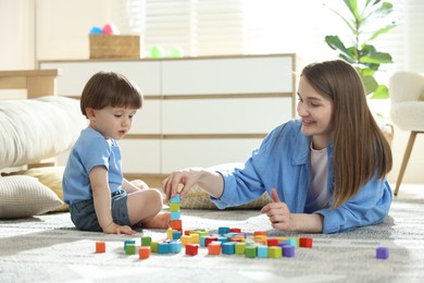 Photo of Mother and son playing with colorful cubes at home