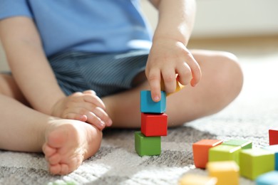 Photo of Cute little child playing with colorful cubes at home, closeup