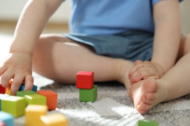 Photo of Cute little child playing with colorful cubes at home, closeup