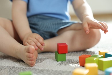 Photo of Cute little child playing with colorful cubes at home, closeup
