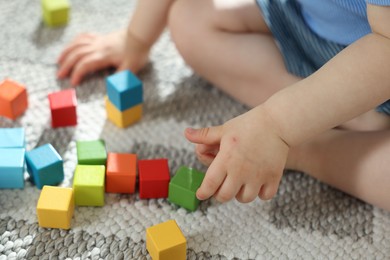 Photo of Cute little child playing with colorful cubes at home, closeup