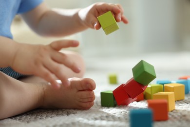 Photo of Cute little child playing with colorful cubes at home, closeup