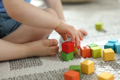 Photo of Cute little child playing with colorful cubes at home, closeup