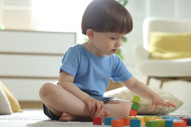 Photo of Cute little child playing with colorful cubes at home