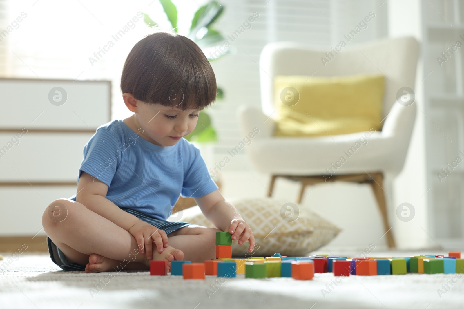 Photo of Cute little child playing with colorful cubes at home. Space for text