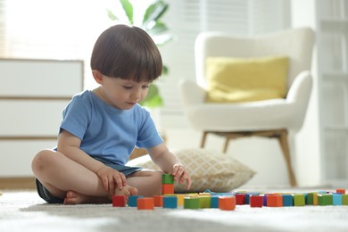 Photo of Cute little child playing with colorful cubes at home. Space for text