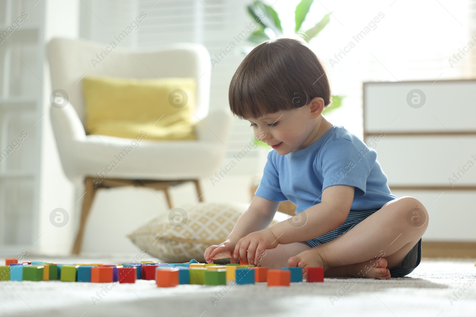 Photo of Cute little child playing with colorful cubes at home. Space for text