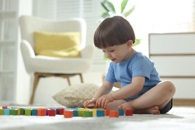 Photo of Cute little child playing with colorful cubes at home. Space for text