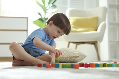 Photo of Cute little child playing with colorful cubes at home