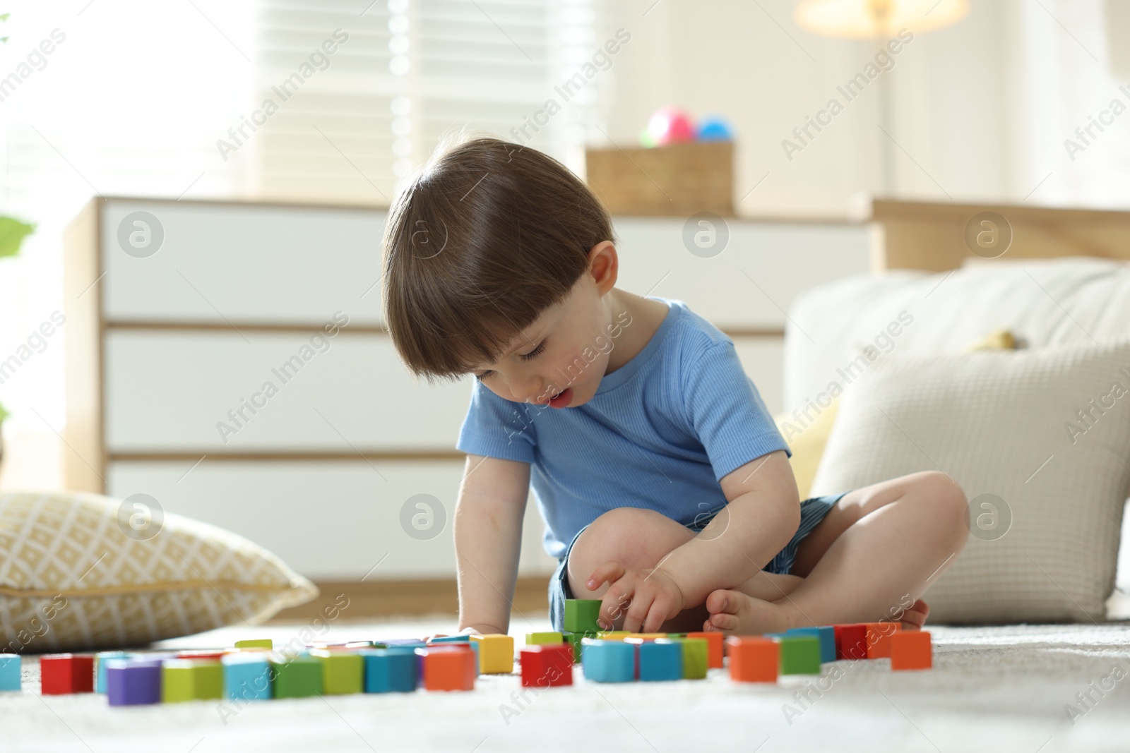 Photo of Cute little child playing with colorful cubes at home