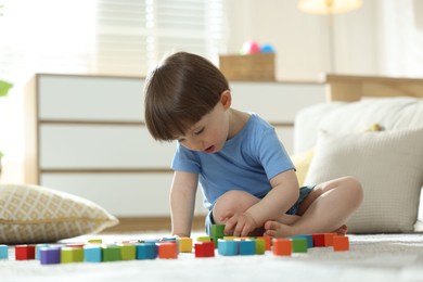 Photo of Cute little child playing with colorful cubes at home