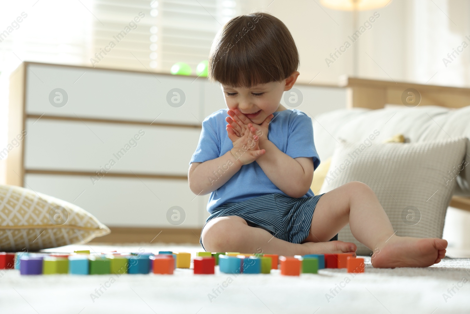 Photo of Cute little child playing with colorful cubes at home