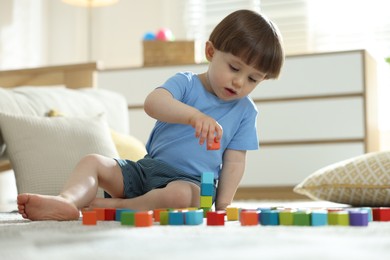 Photo of Cute little child playing with colorful cubes at home
