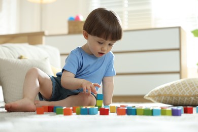 Photo of Cute little child playing with colorful cubes at home