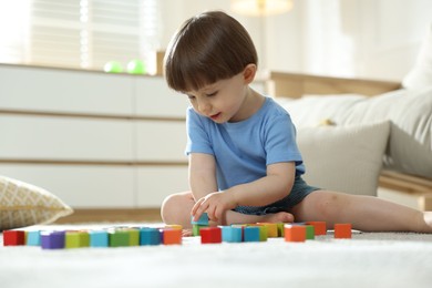 Photo of Cute little child playing with colorful cubes at home