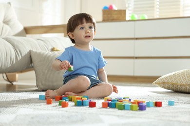 Photo of Cute little child playing with colorful cubes at home. Space for text