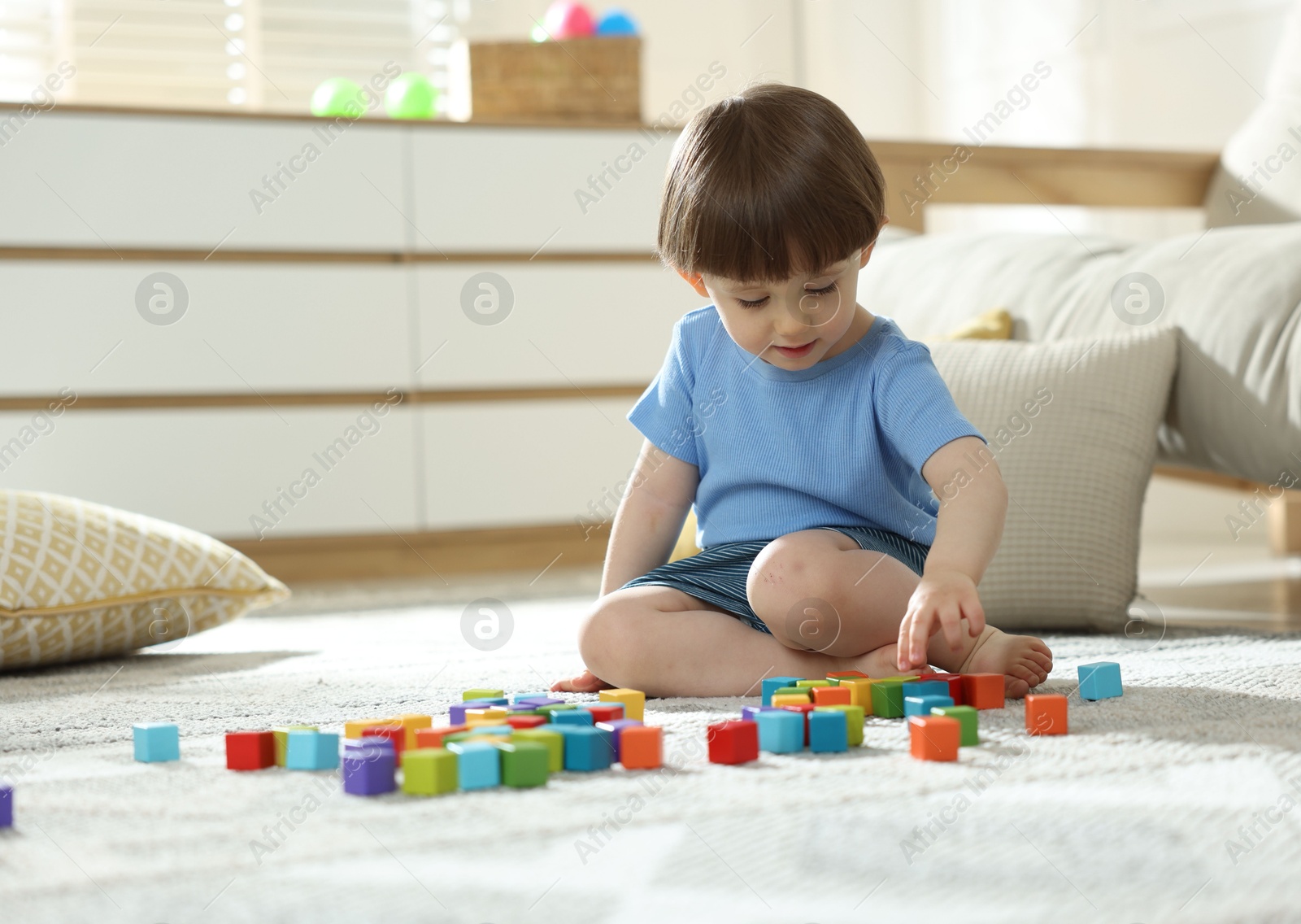 Photo of Cute little child playing with colorful cubes at home. Space for text