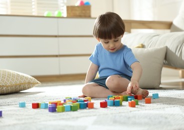 Photo of Cute little child playing with colorful cubes at home. Space for text