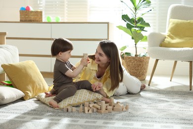 Photo of Mother and son playing with wooden building blocks at home