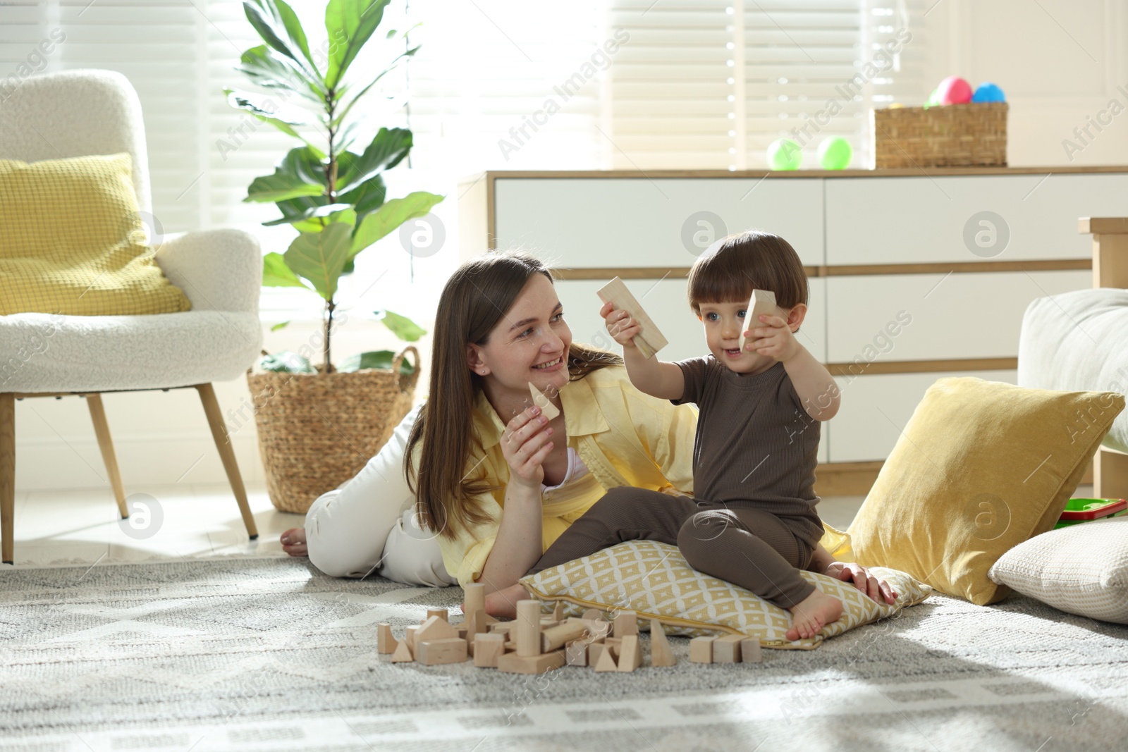 Photo of Mother and son playing with wooden building blocks at home