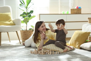 Photo of Mother and son playing with wooden building blocks at home