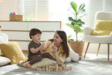 Photo of Mother and son playing with wooden building blocks at home