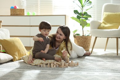 Photo of Mother and son playing with wooden building blocks at home