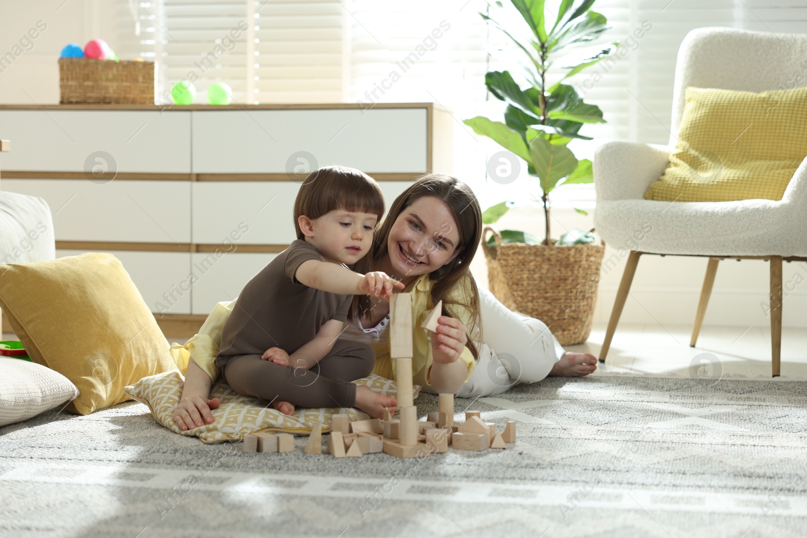 Photo of Mother and son playing with wooden building blocks at home