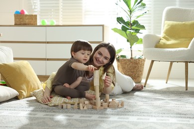 Photo of Mother and son playing with wooden building blocks at home