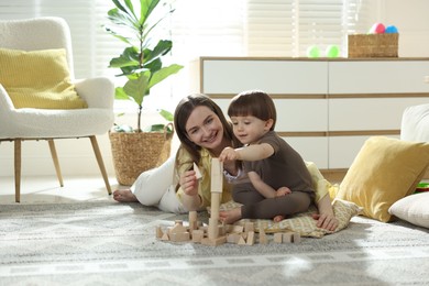 Photo of Mother and son playing with wooden building blocks at home