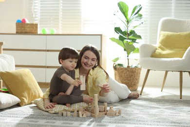Photo of Mother and son playing with wooden building blocks at home. Space for text