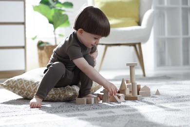Photo of Cute little child playing with wooden building blocks at home