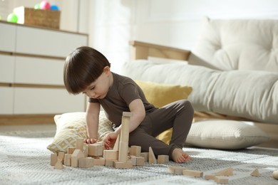 Photo of Cute little child playing with wooden building blocks at home. Space for text