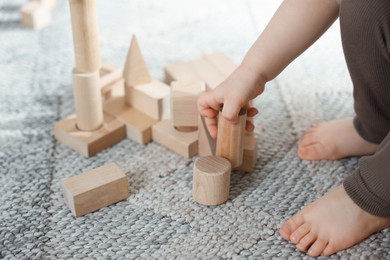 Photo of Cute little child playing with wooden building blocks at home, closeup