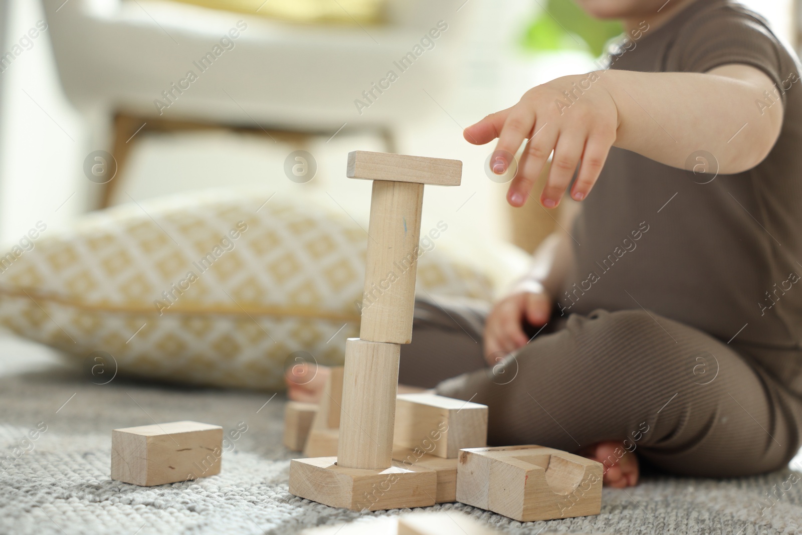 Photo of Cute little child playing with wooden building blocks at home, closeup. Space for text