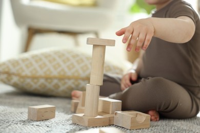 Photo of Cute little child playing with wooden building blocks at home, closeup. Space for text