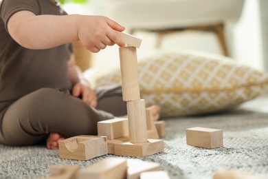 Photo of Cute little child playing with wooden building blocks at home, closeup. Space for text