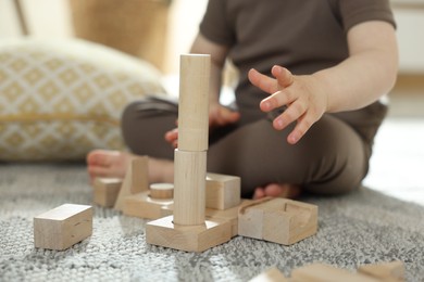 Photo of Cute little child playing with wooden building blocks at home, closeup