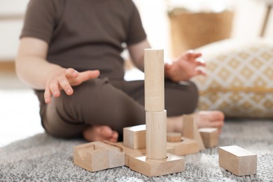 Photo of Cute little child playing with wooden building blocks at home, closeup