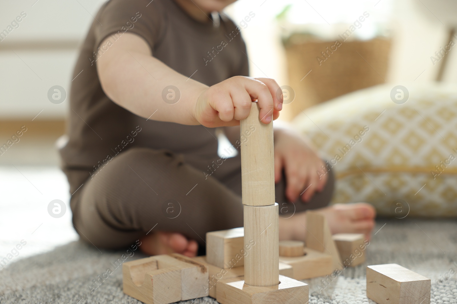 Photo of Cute little child playing with wooden building blocks at home, closeup