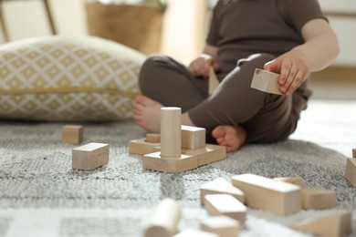 Photo of Cute little child playing with wooden building blocks at home, closeup. Space for text