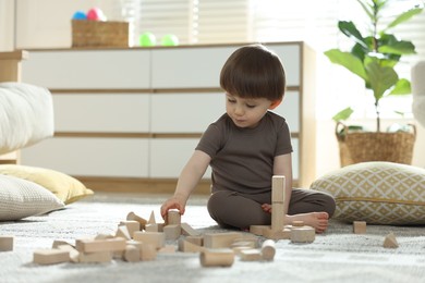 Photo of Cute little child playing with wooden building blocks at home. Space for text