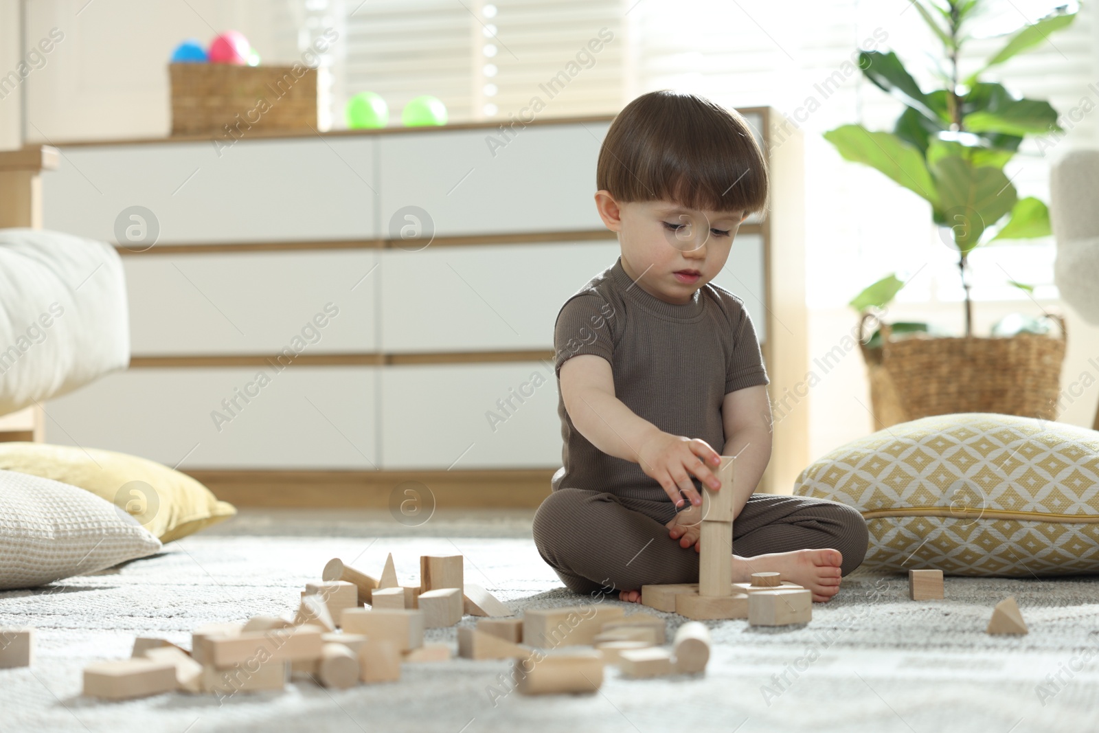 Photo of Cute little child playing with wooden building blocks at home. Space for text