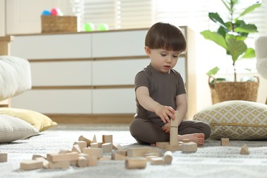 Photo of Cute little child playing with wooden building blocks at home. Space for text