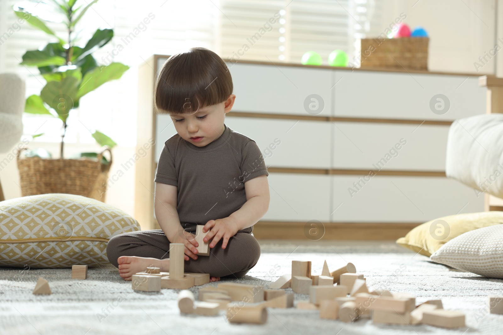 Photo of Cute little child playing with wooden building blocks at home. Space for text