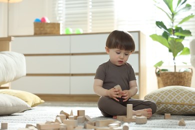Photo of Cute little child playing with wooden building blocks at home. Space for text